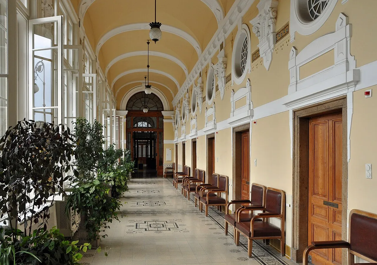 Die leuchtend gelben neobarocken Gebäude des Széchenyi-Heilbades im Stadtwäldchen, mit Badegästen im dampfenden Außenbecken.