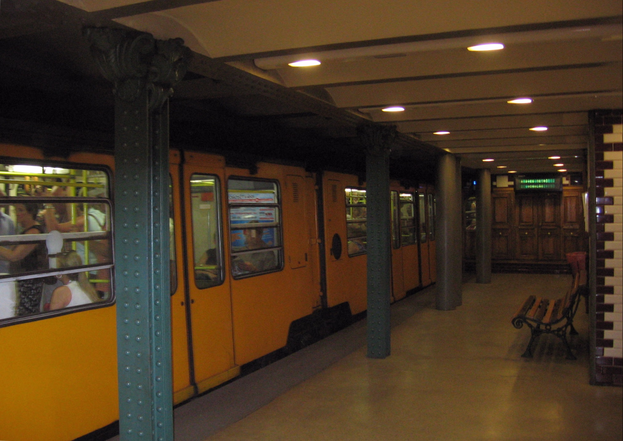 Ein gelber Triebwagen der Linie M1 (Földalatti) am Bahnsteig der Station Vörösmarty utca, mit den charakteristischen grünen Gusssäulen.
