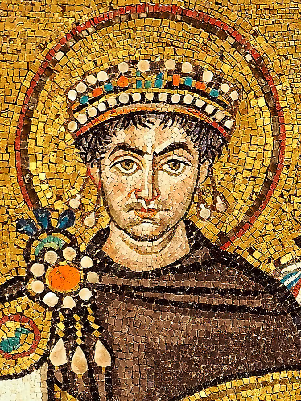 Mosaiktafel in San Vitale: Kaiser Justinian I. in purpurnem Gewand mit goldenem Heiligenschein, umgeben von Klerus, Hofleuten und Soldaten, vor Goldgrund.