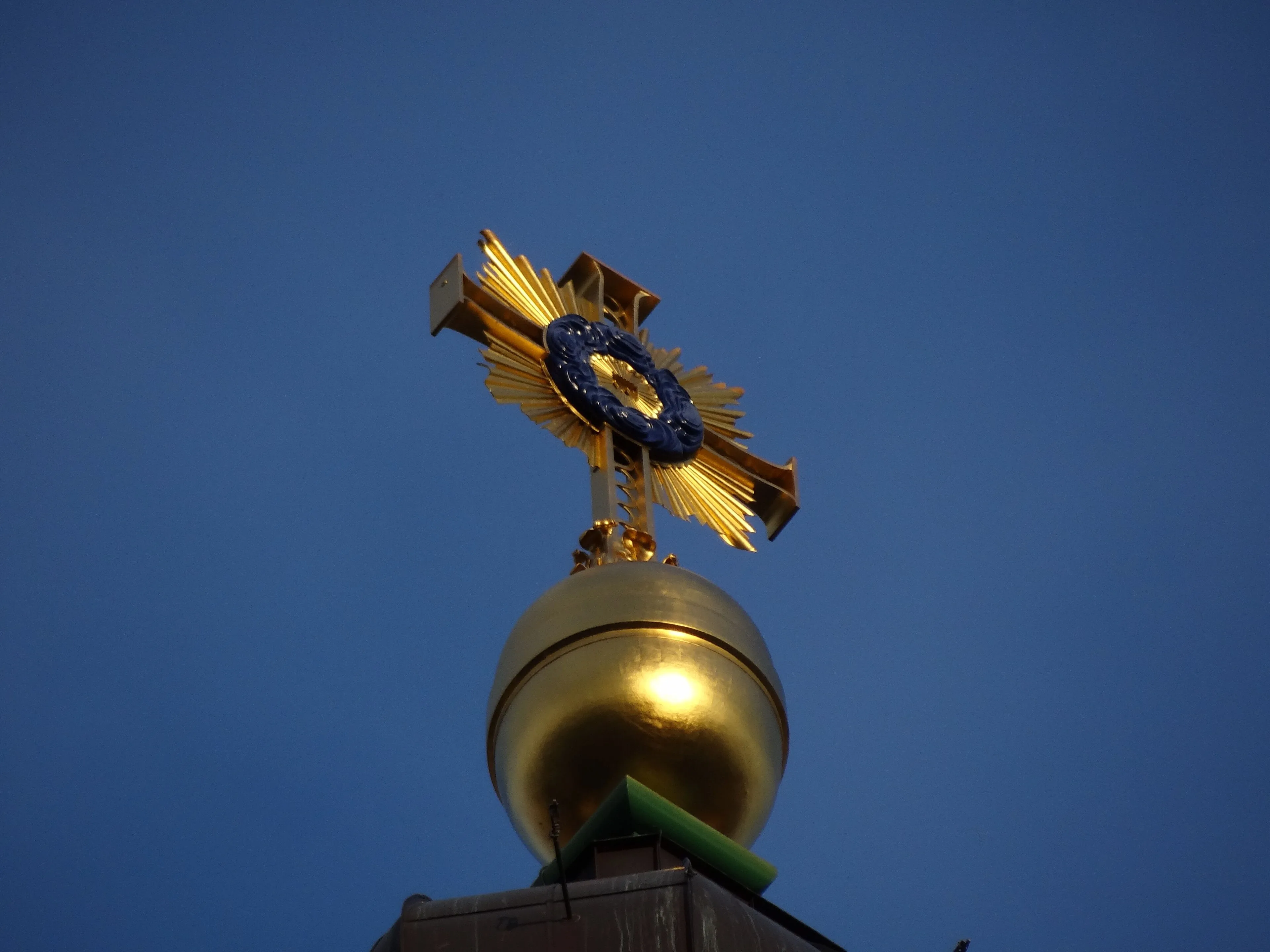 Das neue vergoldete Turmkreuz auf der Laterne der Frauenkirche gegen den Himmel.