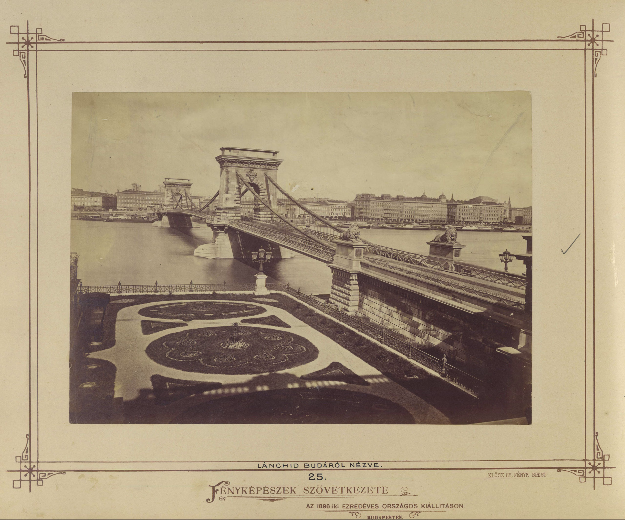 Historisches Schwarzweiß-Foto der Széchenyi-Kettenbrücke von der Budaer Seite aus, aufgenommen zwischen 1873 und 1880: der steinerne Torturm, die durchhängenden Eisenketten und die Fahrbahn über der Donau.