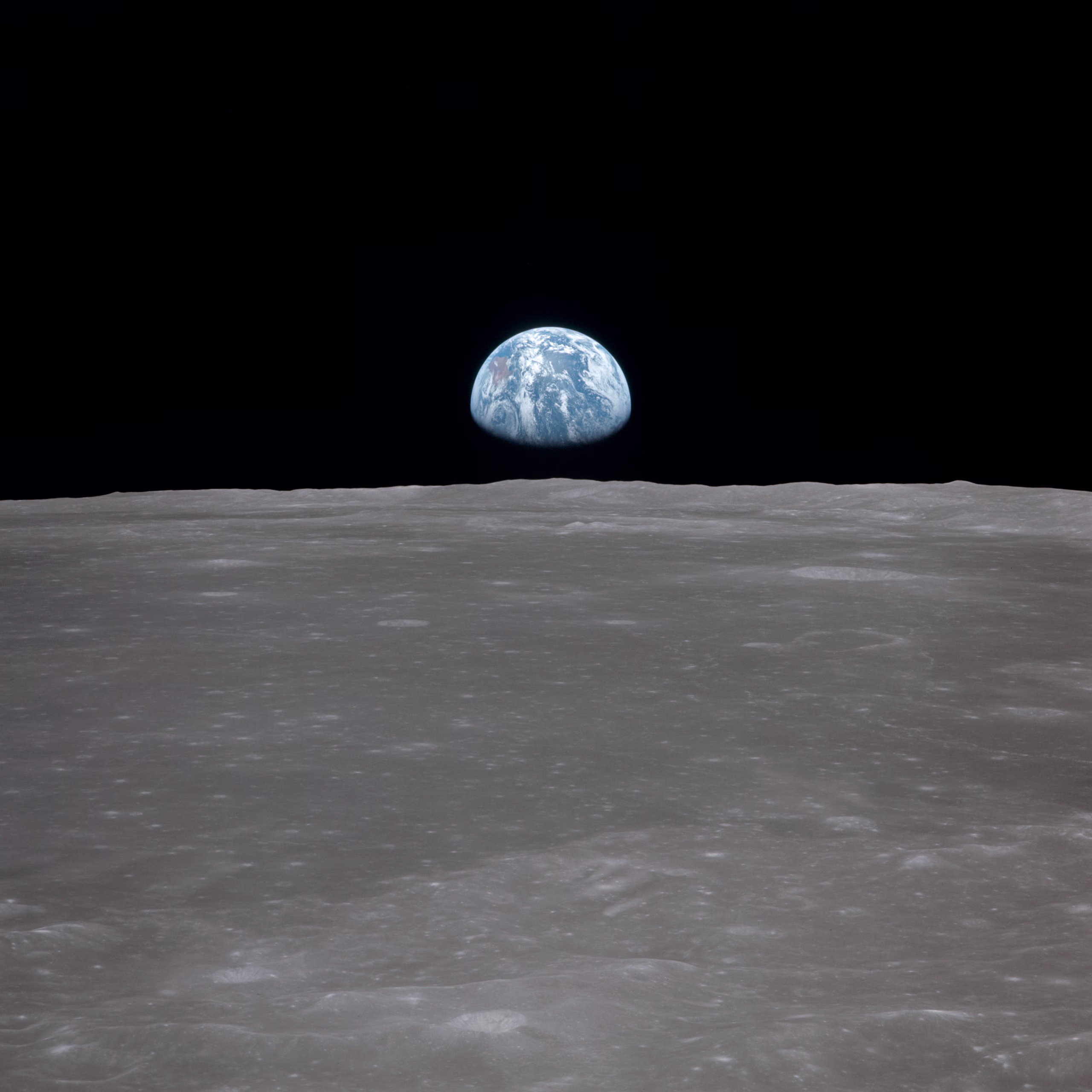 Die Erde steht als blaue Sichel über dem grauen Mondhorizont, aufgenommen aus dem Mondorbit, 1969 (NASA AS11-44-6550)