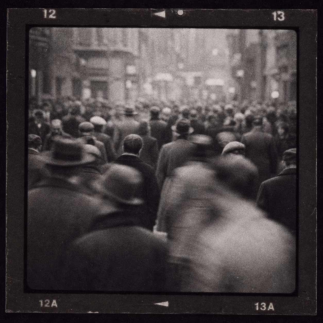 Illustration im Kontaktbogen-Stil — unscharfe, körnige Menschenmenge in Schwarz-Weiß. Keine Aufnahme von Robert Capa oder Gerda Taro; KI-Illustration.