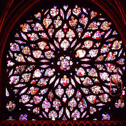 Die Fensterrose der Sainte-Chapelle: ein großes radförmiges Maßwerkfenster mit Szenen der Apokalypse in leuchtendem Glas.